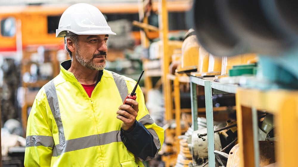 Man in a hard hat with a walkie talkie in a factory